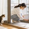 ベランダの猫脱走防止フェンスと床際の隙間を点検する女性