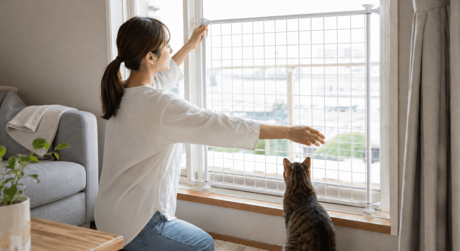 突っ張り式の猫用窓脱走防止フェンスを確認する女性