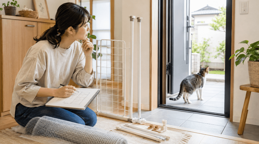 玄関でホームセンターの材料を使った猫の脱走防止対策を考える女性